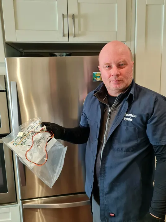 A man holds a bag of wires, ready to address the refrigerator's electrical issues