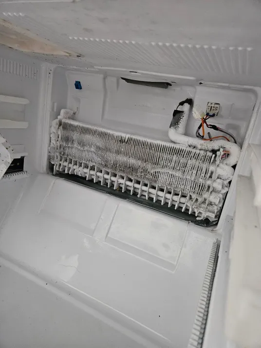 An open refrigerator with a damaged main door and a broken freezer door