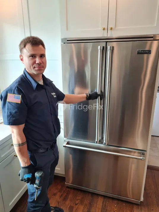 Technician in a uniform gets ready to repair a refrigerator